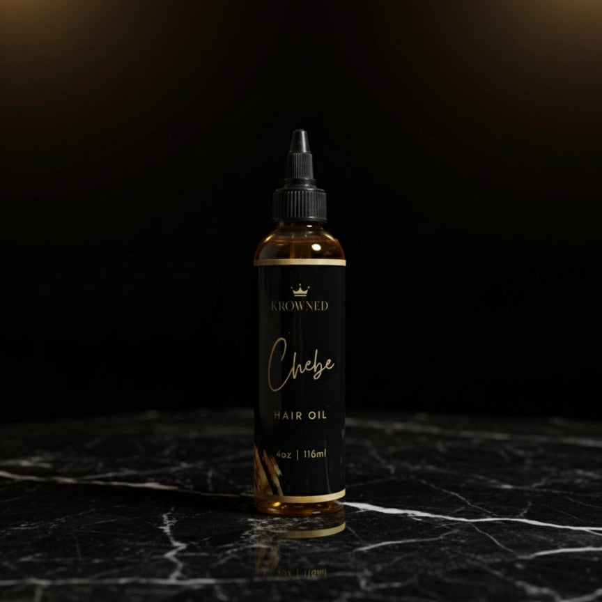 Bottle of Chebe hair oil on a dark marble surface with a dark background