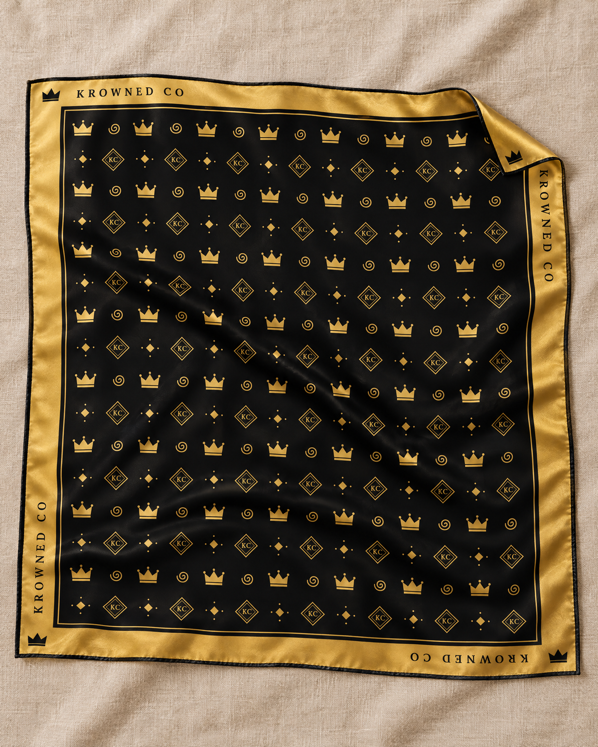 Krowned Signature Satin Head Scarf laid flat, black with gold crown and KC monogram print, Krowned Co logo beside each corner crown